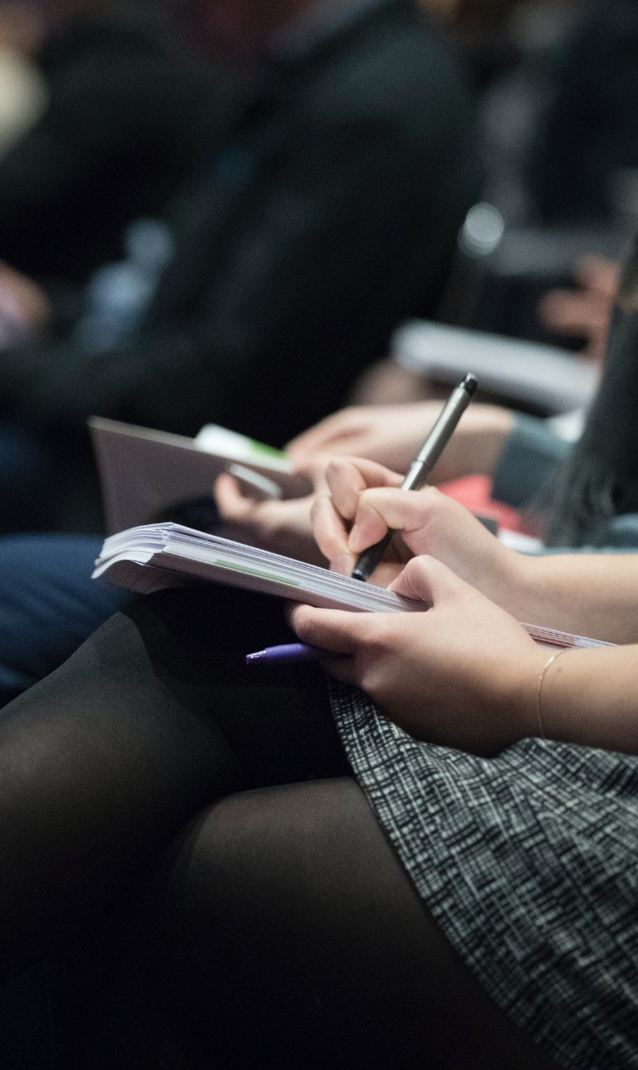 Hand holding onto notepad of paper writing down notes with the other hand